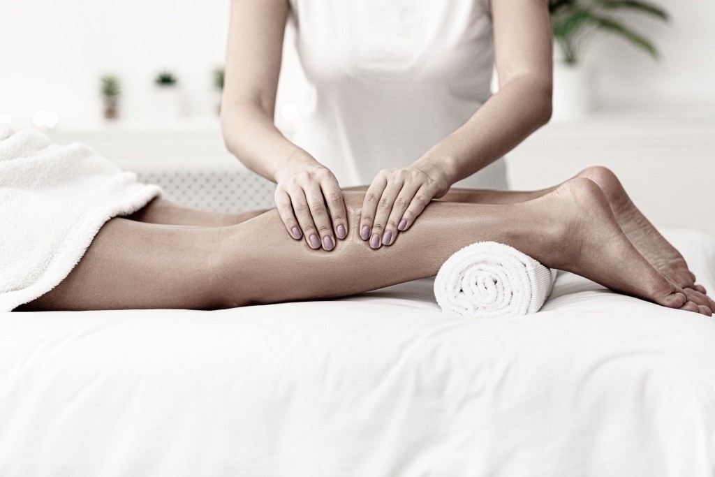 Alpenhaus Kaprun - Wellness, Sport, Erholung - Urlaub im Salzburger Land - Massage therapist massaging woman calves in spa center
